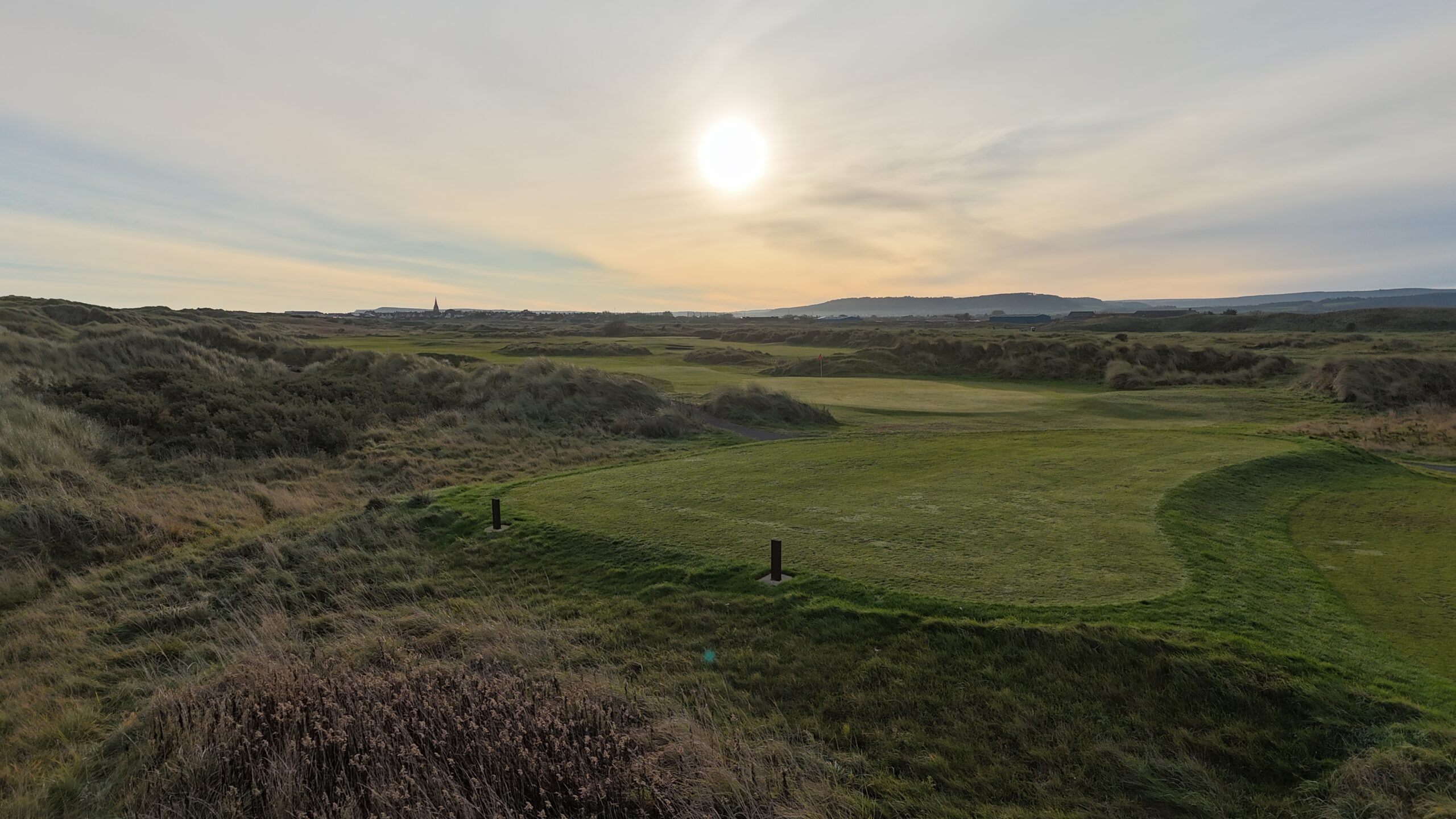 Wide dune-framed links fairway and green at Cleveland Golf Club, lit by low evening sun