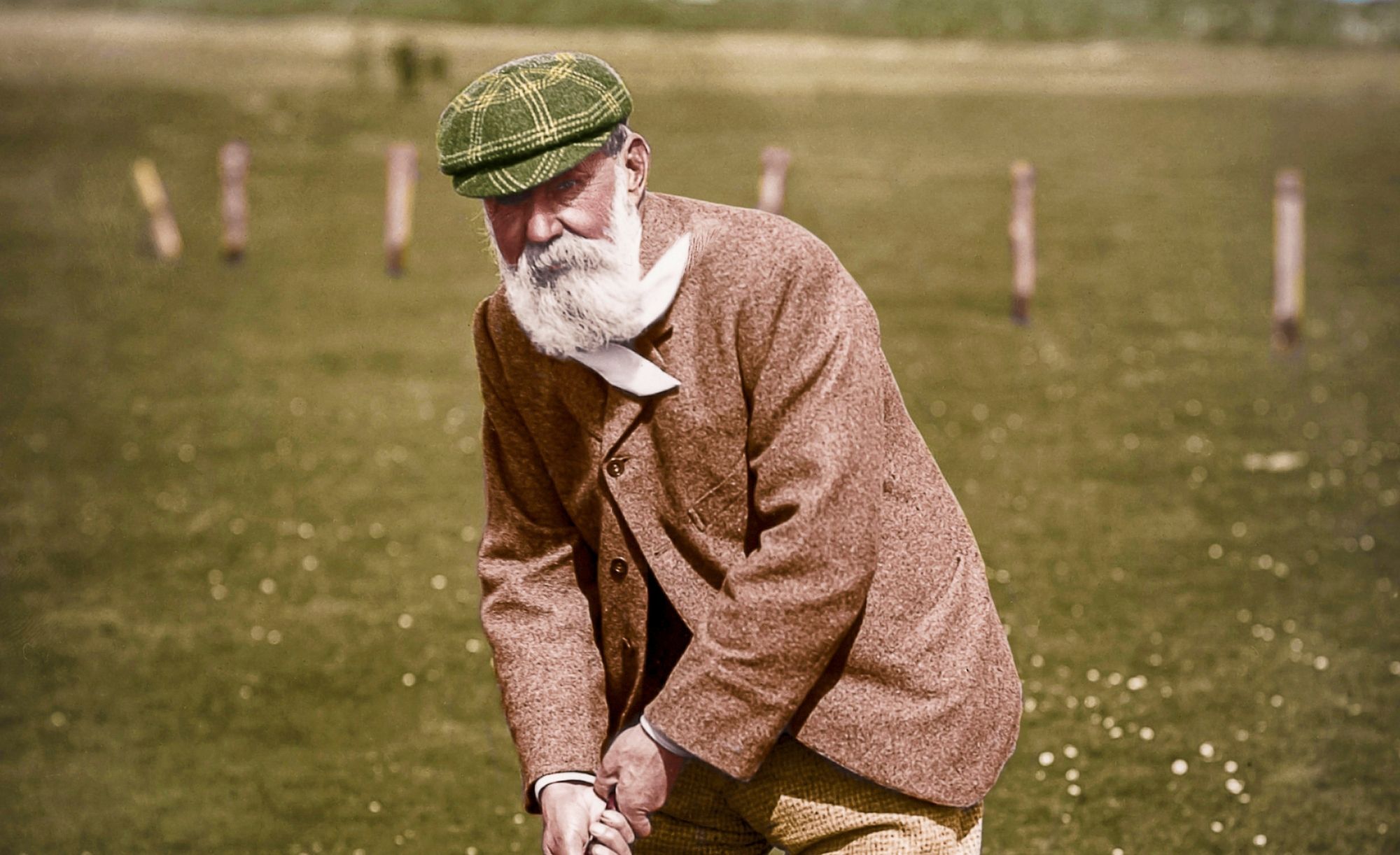 Old Tom Morris standing on a links course, golf club in hand